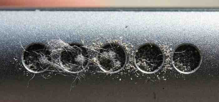  Extreme close-up macro shot of an iPhone speaker grill clogged with grey lint and dust particles